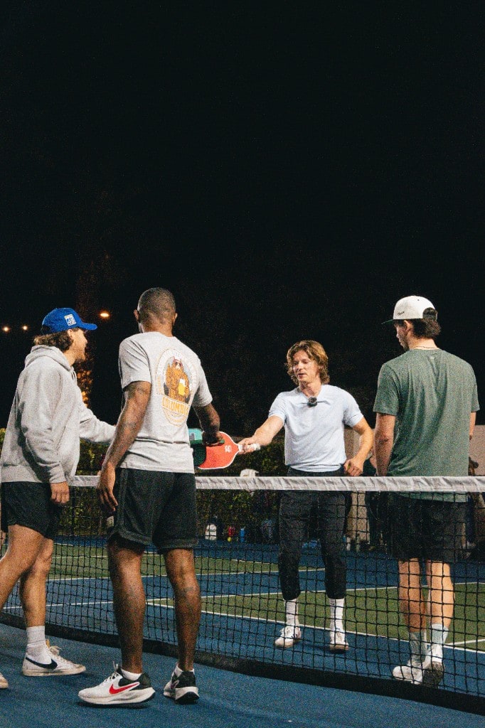 Friends tapping paddles across the net during night play